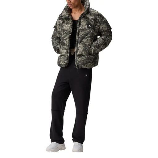 Camouflage print puffer jacket with hood, black pants and white sneakers.