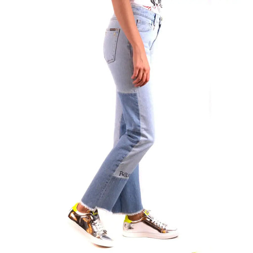 Women wearing Philipp Plein light blue and dark blue patchwork denim jeans with frayed hems and silver sneakers with neon yellow accents