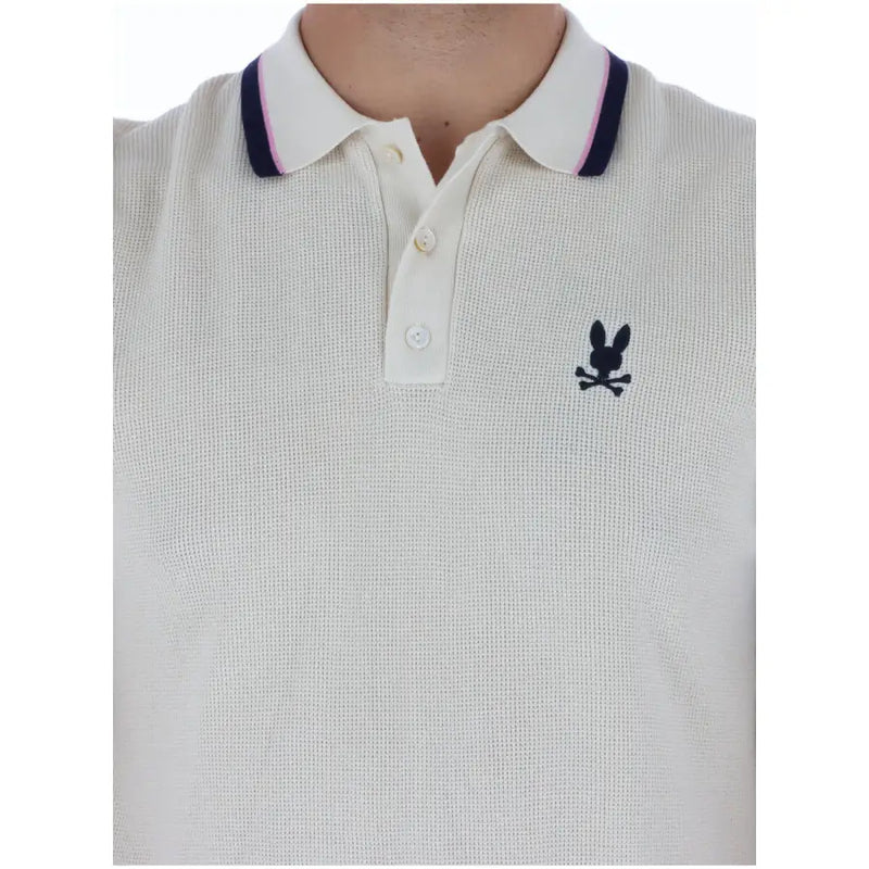 Polo homme en coton crème à motif lapin psychotique, col bordé de rose marine et manches courtes.