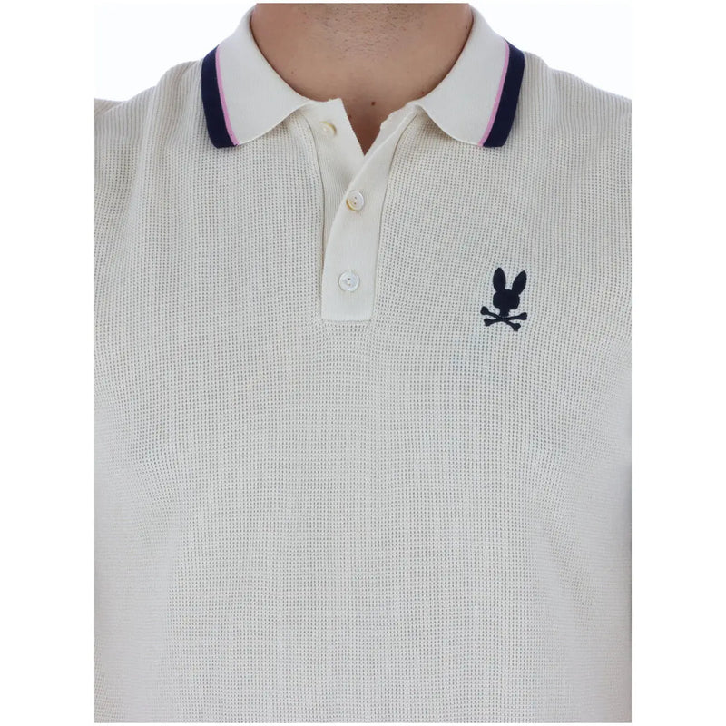 Cream-colored cotton psycho bunny men polo shirt with navy pink collar trim and black embroidered logo short sleeve