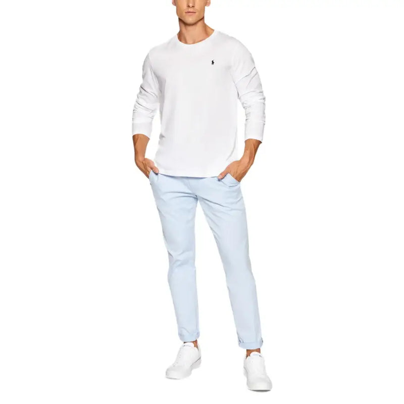 Man wearing light blue casual trousers, white long-sleeve T-shirt, and white sneakers