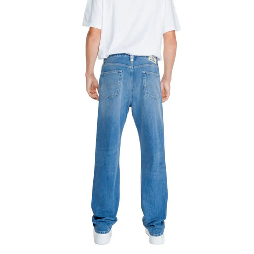 Blue denim straight-leg jeans with a faded wash and white stitching.