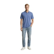 Un homme portant un polo bleu clair à manches courtes, associé à un jean Replay bleu clair slim en coton stretch.