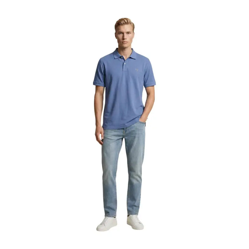 Un homme portant un polo bleu clair à manches courtes, associé à un jean Replay bleu clair slim en coton stretch.
