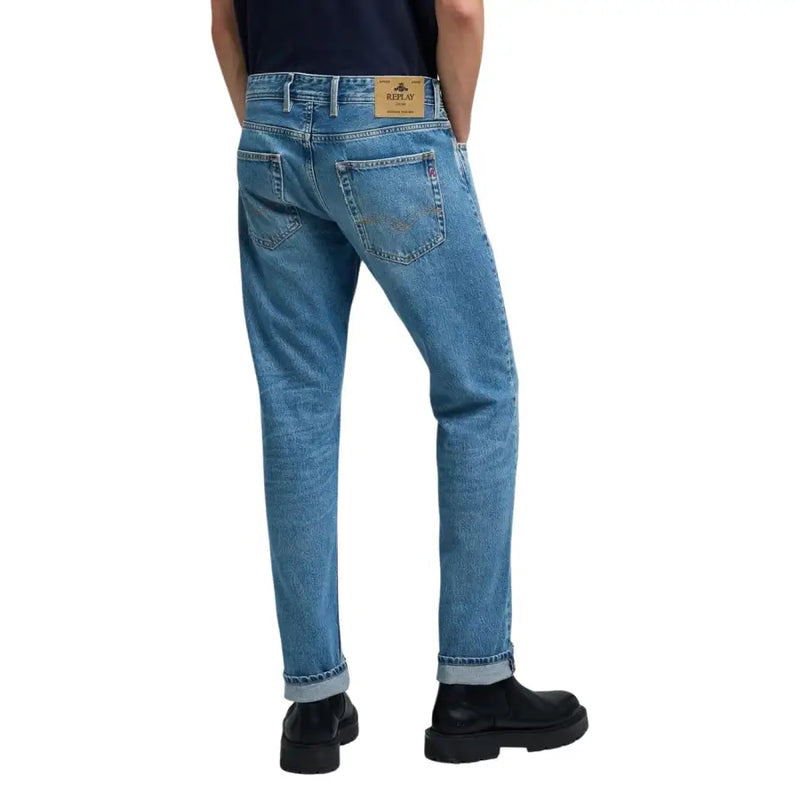Jean homme Replay en denim bleu clair, coupe classique cinq poches, ourlets roulés et étiquette Relay à la ceinture.