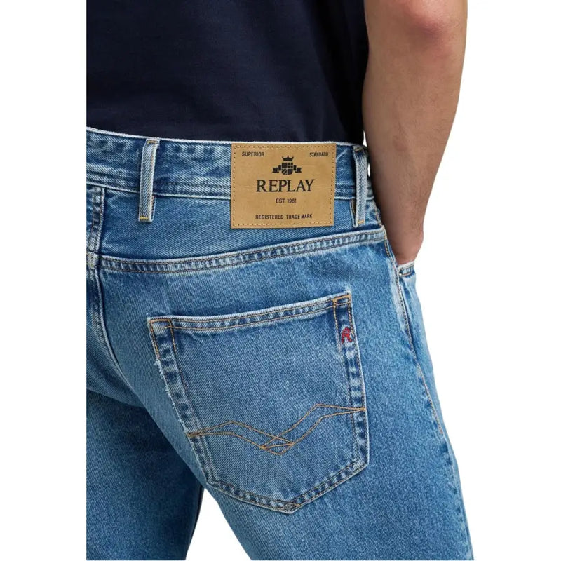Jean homme Replay en denim bleu clair avec écusson de marque en cuir beige et surpiqûres dorées sur la poche (face arrière).