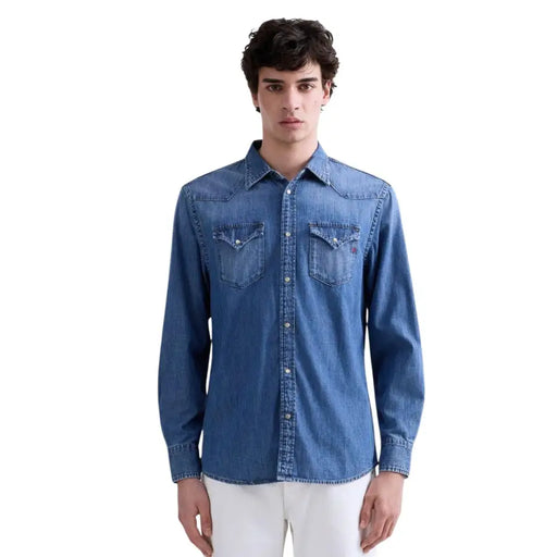 Chemise homme Replay en denim bleu, manches longues, boutonnée, avec deux poches poitrine et logo discret de la marque sur la poche gauche.