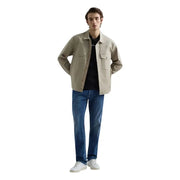 Veste utilitaire beige à boutons et deux poches poitrine, portée avec un jean droit bleu stretch pour homme de la marque Replay.