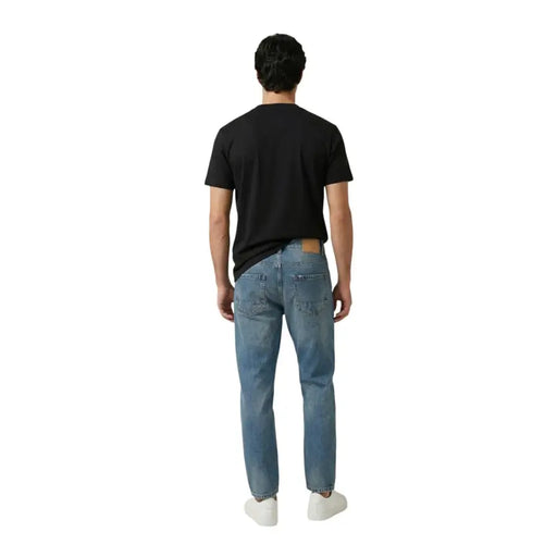 Replay hommes t-shirt associé à un jean en denim clair délavé, doté d'une coupe classique à cinq poches et d'un empiècement en cuir à l'arrière de la ceinture.