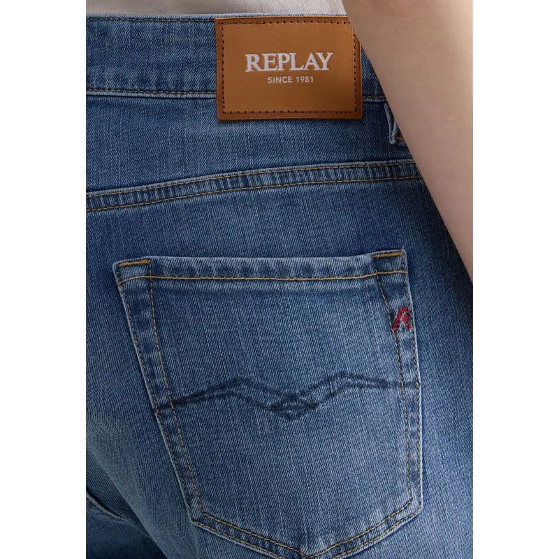 Jean slim en coton bleu pour femme Replay, avec étiquette de marque en cuir marron et logo brodé rouge sur la poche.