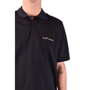 Polo Saint Laurent en coton noir pour homme, orné d'une broderie dorée « Sweet Dreams » sur la poitrine gauche (vue de face).