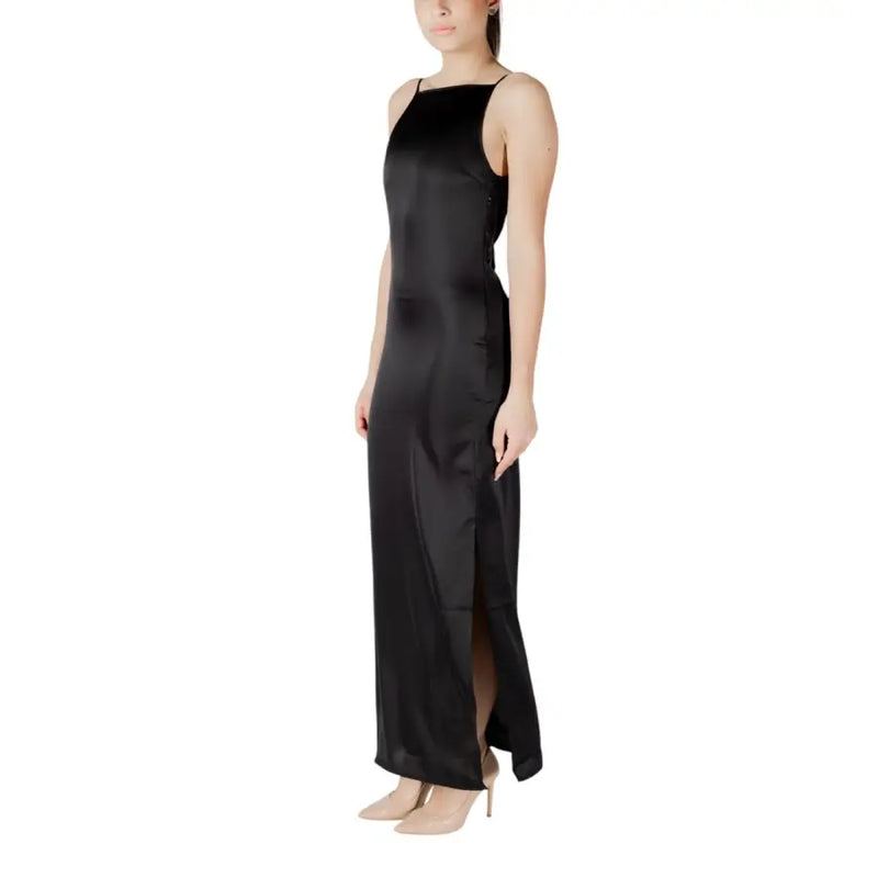 A sleeveless black satin maxi dress with thin spaghetti straps and a high side slit