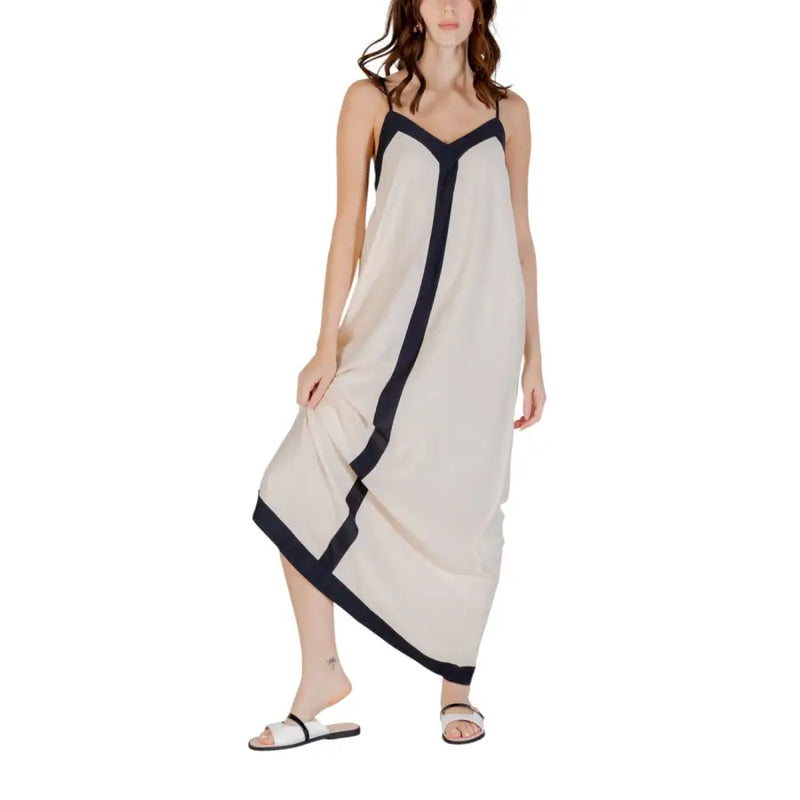 A flowing off-white sleeveless floor length dress with sleek black trim along neckline sides and hem