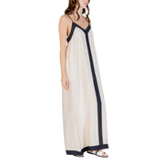 A flowing off-white sleeveless floor length dress with navy blue trim on straps front panel and hemline