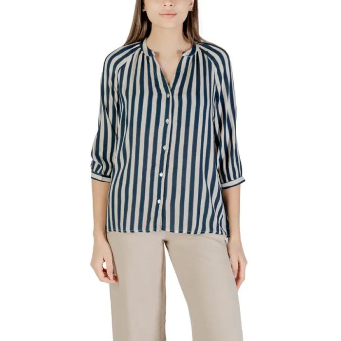 Animal print blouse with three-quarter sleeves paired with striped button-down shirt and beige pants