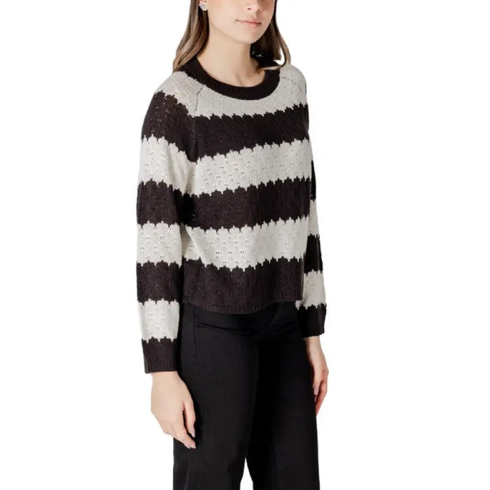 Women’s striped knit sweater displayed with black pants in a fashion product image