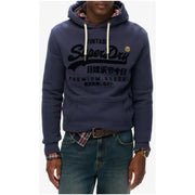Navy blue Superdry men’s printed hooded sweatshirt with front pockets worn over plaid shirt and jeans