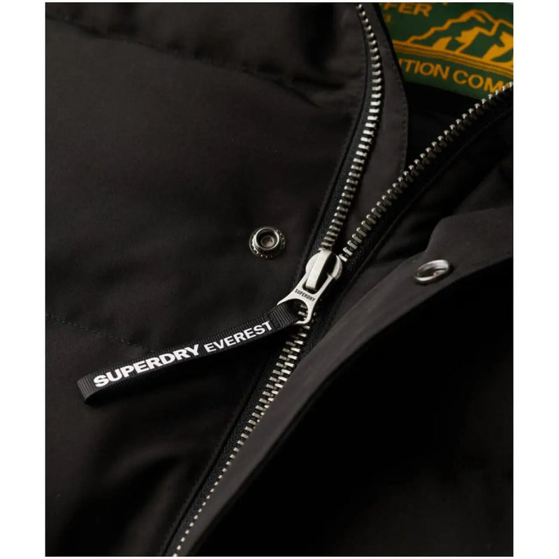 Tirette de fermeture éclair pour doudoune Superdry Everest noire avec inscription blanche, sur une longue veste d'hiver à capuche pour homme, référence M5011743a