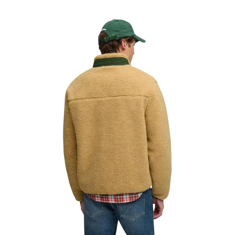 Veste en peau lainée beige avec col vert foncé et casquette assortie, portée avec un sweat-shirt polaire zippé jaune Superdry pour homme