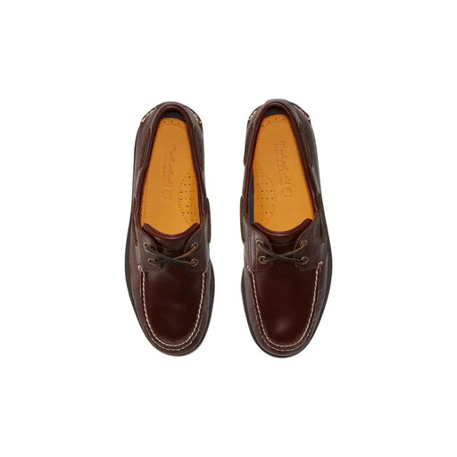 Timberland Mocassins en cuir marron pour homme, style bateau, avec surpiqûres blanches contrastantes et semelles intérieures beiges.