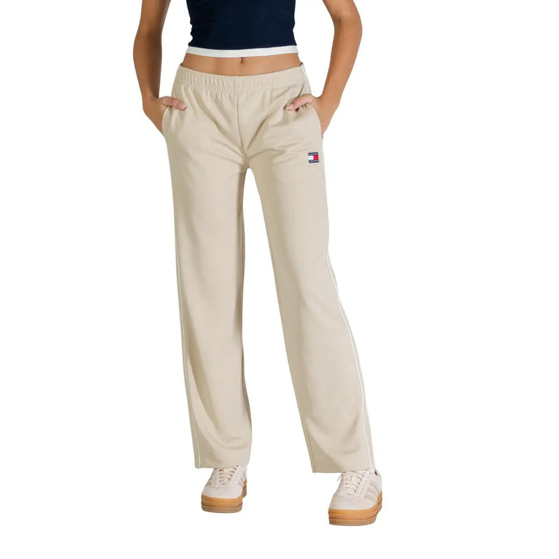 Pantalon de survêtement beige Tommy Hilfiger avec bandes latérales blanches et petit logo sur la cuisse gauche, idéal pour la collection printemps-été femme.