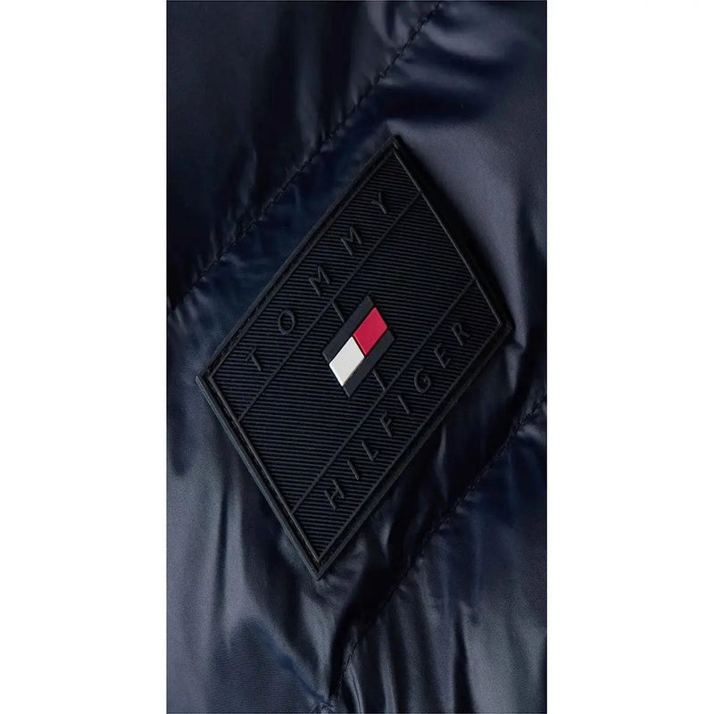 Écusson Tommy Hilfiger noir en forme de losange avec logo et drapeau en relief sur une doudoune en polyamide bleu marine