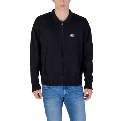 Black bomber jacket with zipper and logo patch on chest.