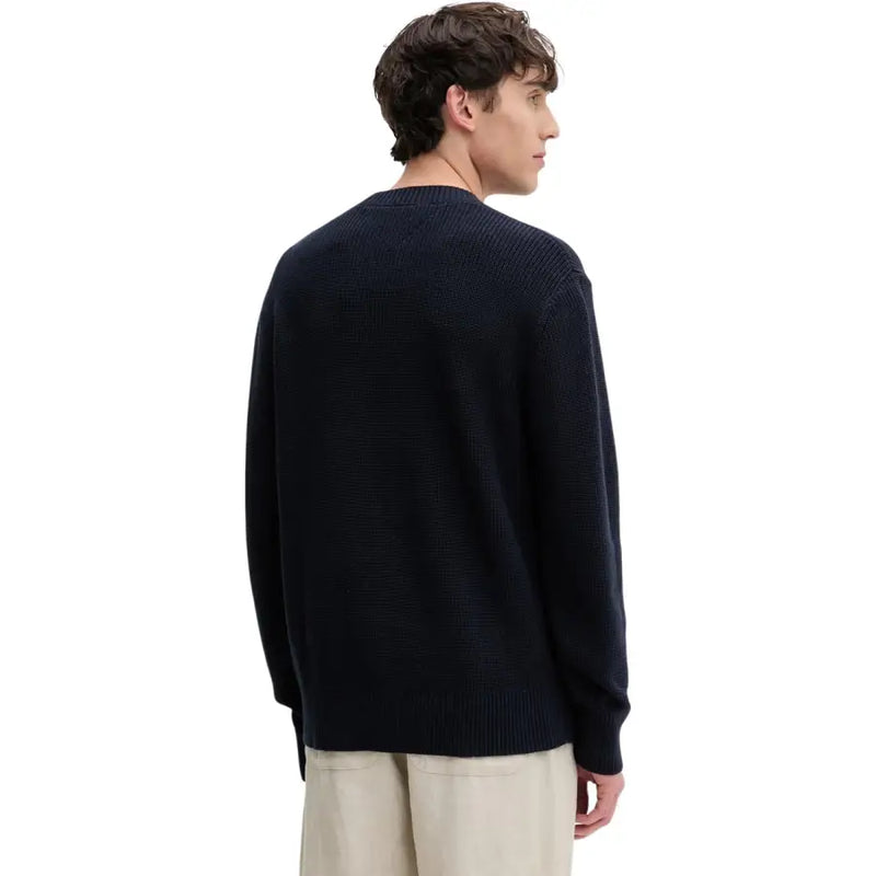 Un pull en maille côtelée bleu marine à col rond et manches longues, confectionné en coton biologique par Tommy Hilfiger Jeans