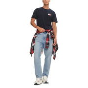 Man wearing navy blue Tommy Hilfiger T-shirt with light blue jeans and plaid shirt tied around waist