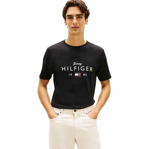 T-shirt homme Tommy Hilfiger Jeans en coton noir, orné du logo Tommy Hilfiger 1985 blanc et de l'emblème de la marque.