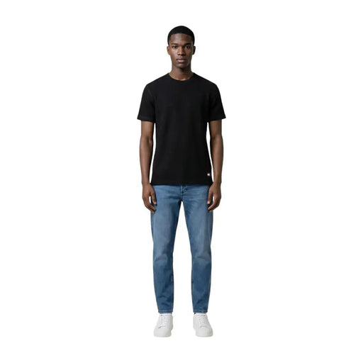 T-shirt noir à manches courtes et col rond en coton t-shirt avec un petit logo rouge et blanc en bas à gauche par Tommy Hilfiger Jeans