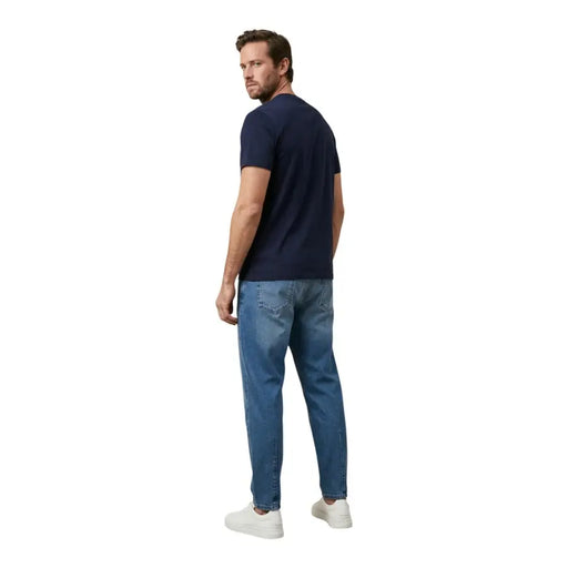 Un homme portant un t-shirt Tommy Hilfiger bleu marine à manches courtes t-shirt et jeans en denim délavé moyen pour hommes