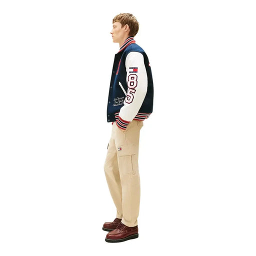 Veste universitaire bleu marine et blanche avec bordures à rayures rouges, blanches et bleues et numéro 85 brodé sur la manche, pour homme, par Tommy Hilfiger