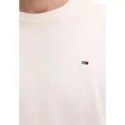 Pull ras du cou en maille couleur crème, confectionné en coton biologique et orné du logo Tommy Hilfiger brodé sur la poitrine gauche.