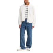 Men wearing a white fleece zip-up jacket, striped t-shirt, and blue wide-leg jeans