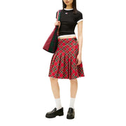 Jupe plissée à carreaux rouges avec des accents verts et noirs, portée avec un jean Tommy Hilfiger noir en coton biologique pour femme t-shirt