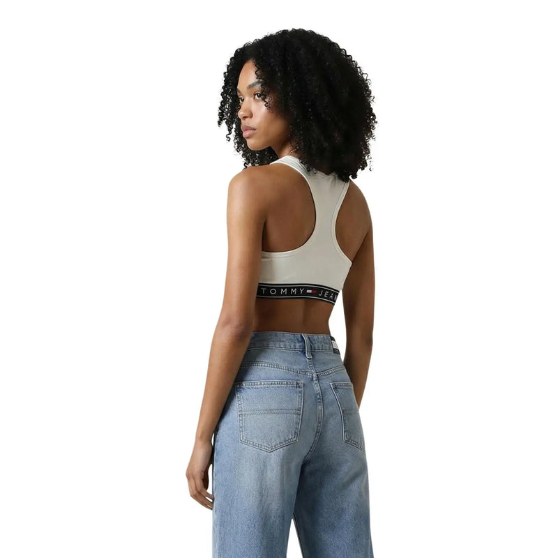 Soutien-gorge de sport couleur crème Tommy Jeans avec bande élastique noire et logo, faisant partie de la collection Tommy Hilfiger Jeans femme sans manches à col rond blanc top