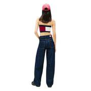 Une femme portant un jean Tommy Hilfiger bleu foncé à jambes larges en coton biologique avec logo à l'arrière de la ceinture et une casquette rose