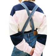 Tommy hilfiger light blue denim jumpsuit for women with crossed shoulder straps worn over a color-blocked sweatshirt