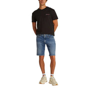 Black t-shirt with white logo, denim shorts, and beige sneakers.
