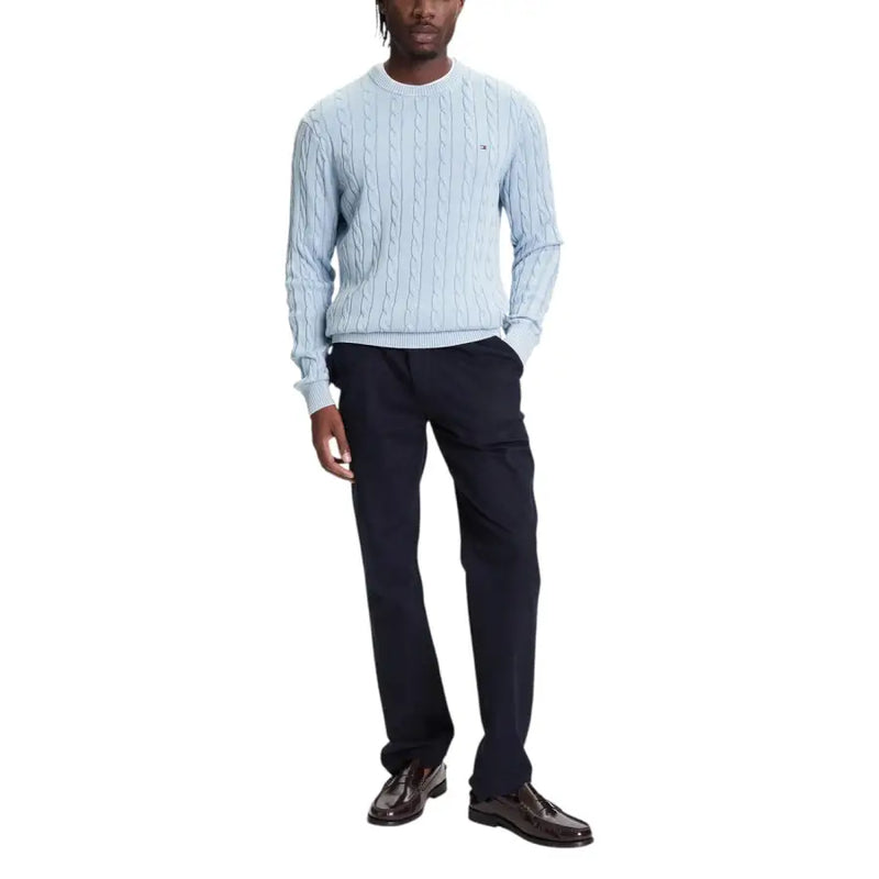 Light blue cable-knit sweater with navy pants and black shoes.