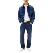 Jean Tommy Hilfiger pour homme en coton biologique bleu, porté avec une veste en jean bleu foncé à boutons et poche poitrine.