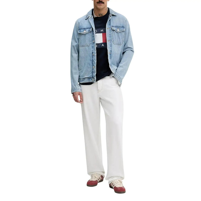 Veste en jean délavé clair avec fermeture boutonnée classique et poches poitrine, portée avec un t-shirt bleu en coton bio Tommy Hilfiger.