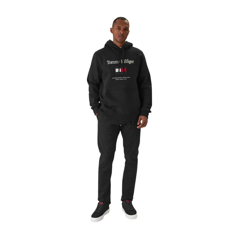 Tommy Hilfiger Sweat à capuche noir en coton mélangé pour homme, avec logo blanc et emblème du drapeau rouge, blanc et bleu sur la poitrine.