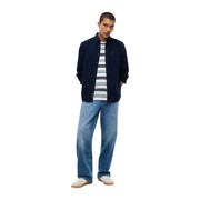 Tommy Hilfiger Chemise en jean bleu coton pour homme, style décontracté, portée avec une chemise boutonnée bleu marine et un t-shirt rayé sur un jean clair.