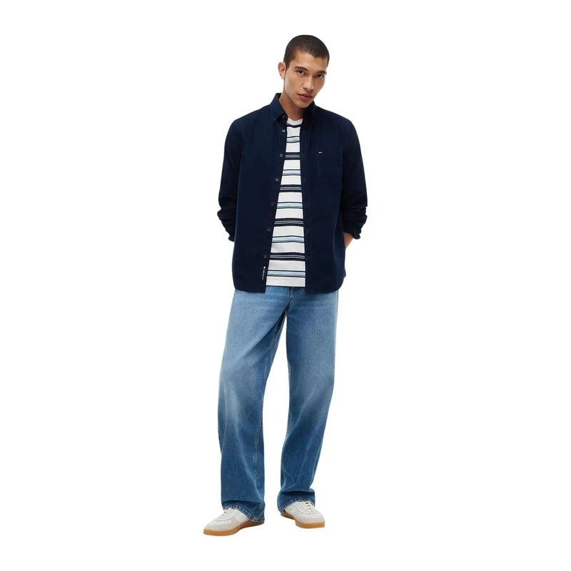 Tommy Hilfiger Chemise en jean bleu coton pour homme, style décontracté, portée avec une chemise boutonnée bleu marine et un t-shirt rayé sur un jean clair.