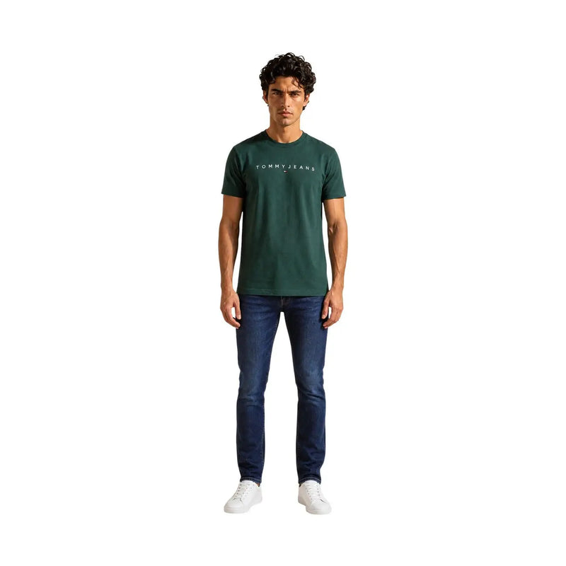 Tommy Hilfiger T-shirt homme vert en coton bio, coupe classique, porté avec un jean Tommy vert foncé et un logo blanc sur la poitrine.