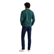 Un homme portant un Tommy Hilfiger Sweat-shirt en molleton de coton vert pour homme, porté avec un jean bleu marine dans une tenue décontractée.