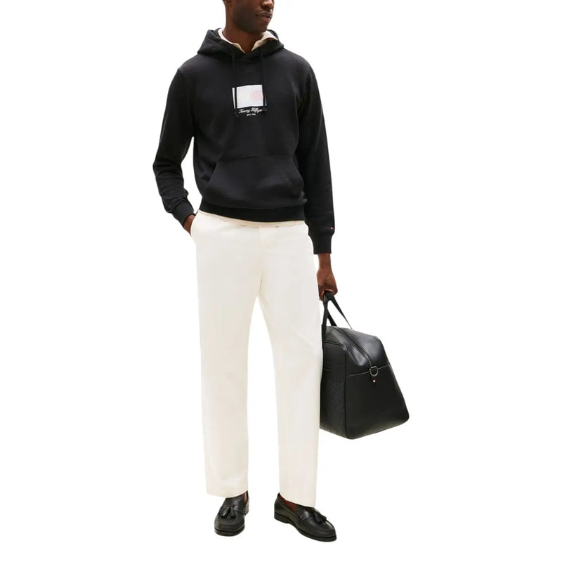 Black leather duffel bag with single front buckle and top handles paired with tommy hilfiger men hoodie black organic cotton