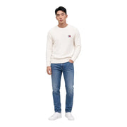 Un pull Tommy Hilfiger couleur crème en coton biologique, à col rond, avec un petit logo brodé sur la poitrine gauche.